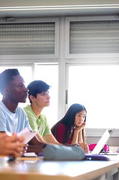Vertical image of asian female teen college student in class listening to lecture with multiracial classmates. Copy space. Education concept. Back to school.
