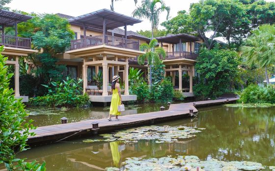 Asian women with a hat walking in a tropical garden during vacation. Young women in a tropical garden