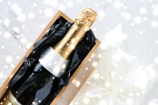 New Years Eve, happy holidays and luxury present concept - Christmas holiday champagne bottle and a gift box and shiny snow on marble background