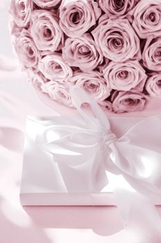 Happy holidays, luxe shopping and love gifts concept - Luxury holiday silk gift box and bouquet of roses on blush pink background, romantic surprise and flowers as birthday or Valentines Day present