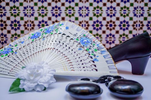 typical spanish flamenco accessories castanets,fan,and high heels on a white table