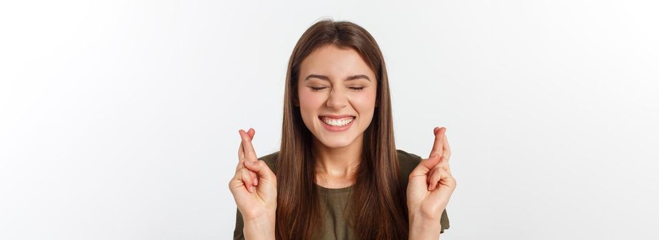 Closeup portrait hopeful beautiful woman crossing her fingers, open eyes, hoping, asking best isolated on gray wall background