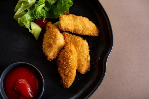 Fried chicken breast nuggets, on lettuce leaves, with tomato sauce, horizontal, no people.