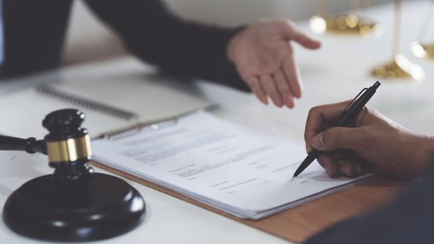 Business woman and lawyers discussing contract papers with brass scale on wooden desk in office. Law, legal services, advice, Justice concept.