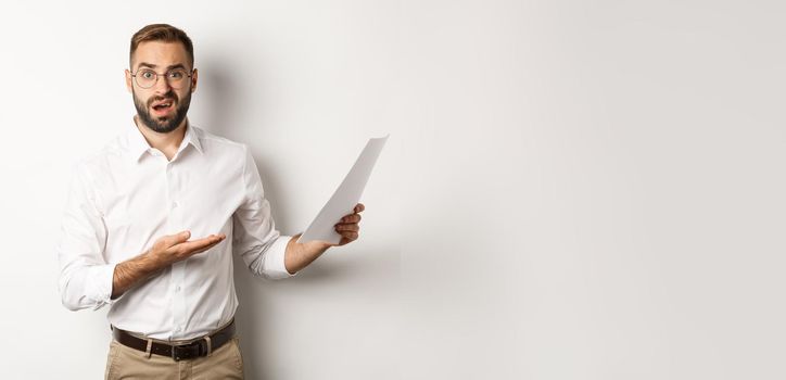Disappointed boss scolding for bad report, pointing at documents and looking confused, standing over white background.