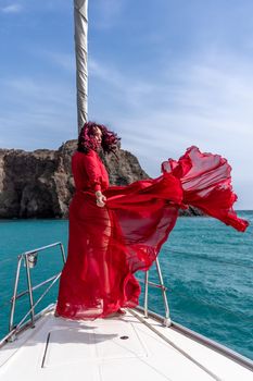 Attractive middle-aged woman in a red dress on a yacht on a summer day. Luxury summer adventure, outdoor activities