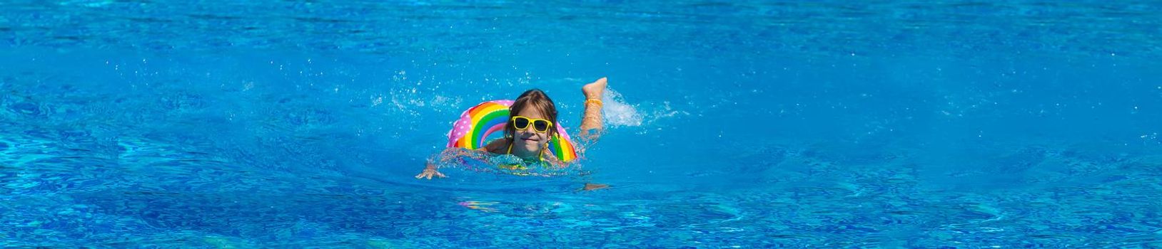 The child swims with a circle in the pool. Selective focus. Kid.