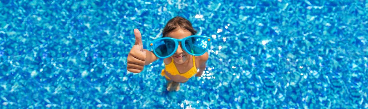 The child is swimming in the pool. Selective focus. Kid.