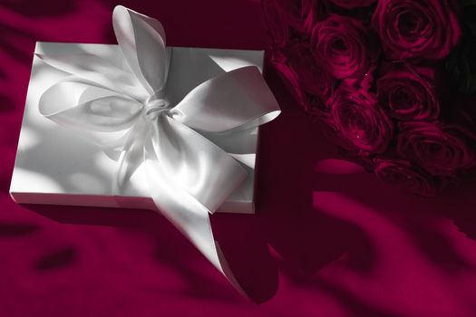 Happy holidays, luxe shopping and love gifts concept - Luxury holiday silk gift box and bouquet of roses on wine background, romantic surprise and flowers as birthday or Valentines Day present