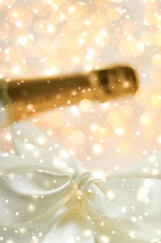 Christmas time, happy holidays and luxury present concept - New Years Eve holiday champagne bottle and a gift box and shiny snow on marble background
