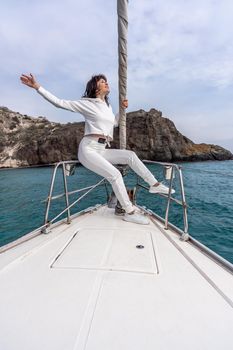 Woman standing on the nose of the yacht at a sunny summer day, breeze developing hair, beautiful sea on background.