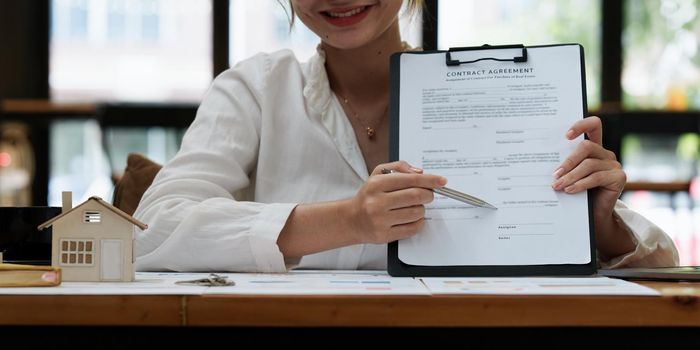 Business woman or broker checking contract agreement paper with customer to sign contract. Real Estate and Agreement concept.