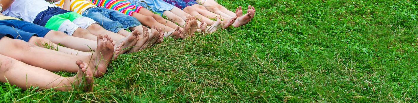 Children's feet lie on the grass. Selective focus. Kid.