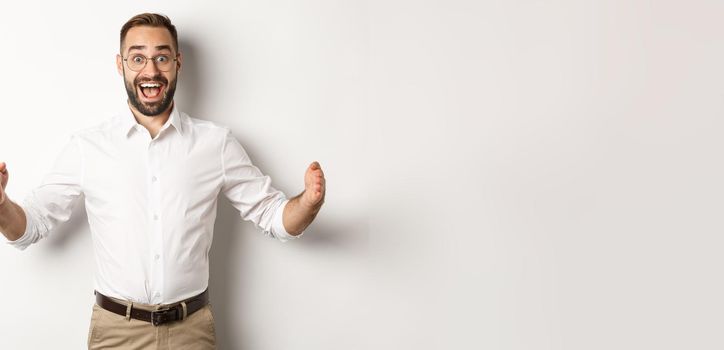 Amazed businessman showing big object, describe something large and looking excited, standing over white background.