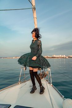 Woman standing on the nose of the yacht at a sunny summer day, breeze developing hair, beautiful sea on background.