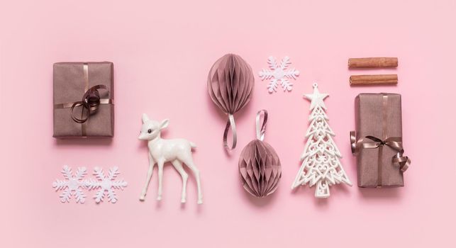 Festive minimal creative christmas composition with gifts, paper balls and xmas tree flat lay on pink background.