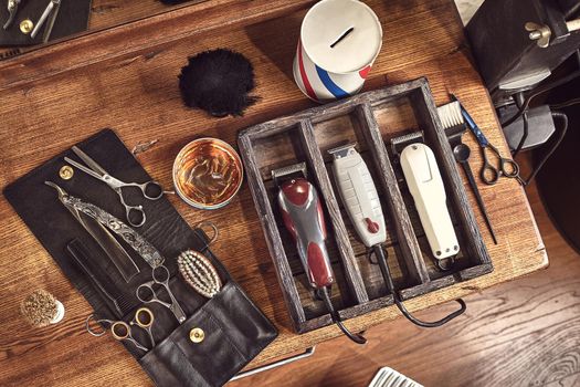 Hairdresser tools on wooden background. Top view on wooden table with scissors, comb, hairbrushes and hairclips, trimmer. Barbershop, manhood concept