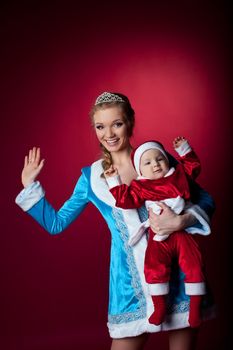 Beauty christmas girl in blue cloth play with baby santa claus