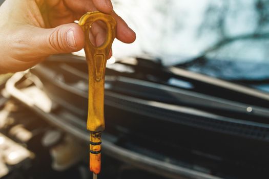 Dirty yellow handle from a car engine dipstick in hand.
