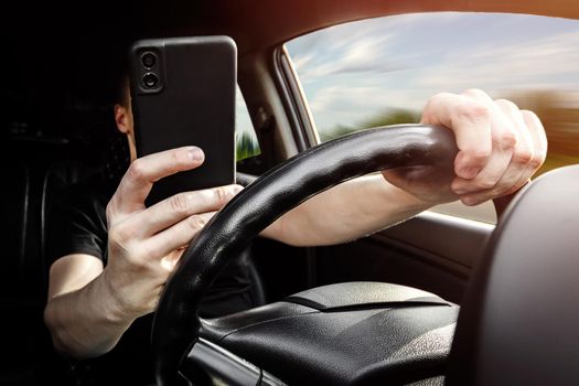 The driver at the wheel of a car uses a smartphone, distracted from the road.