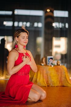 Meditation and concentration. a woman in a red dress, sitting on the floor with her eyes closed, is practicing medicine indoors. Peace and relaxation.