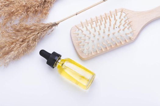 Oil for hair growth. Therapeutic oil to activate hair growth. Comb on white background. Hair care. Beauty and health.