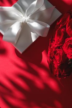 Happy holidays, luxe shopping and love gifts concept - Luxury holiday silk gift box and bouquet of roses on red background, romantic surprise and flowers as birthday or Valentines Day present