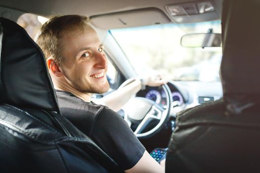 Self-employed caucasian smiling driver in his car taxis or works on delivery.