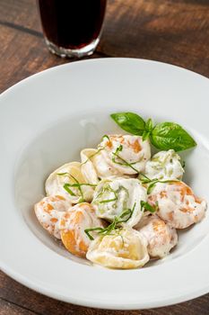 different types of pelmeni or russian dumplings in white plate on wooden background