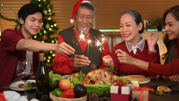 Happy family with sparklers celebrating Christmas together in cozy home. Celebration, holidays and Christmas concept.