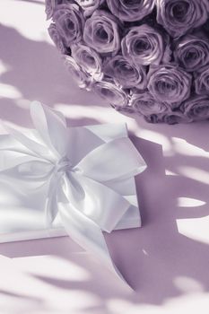 Happy holidays, luxe shopping and love gifts concept - Luxury holiday silk gift box and bouquet of roses on purple background, romantic surprise and flowers as birthday or Valentines Day present