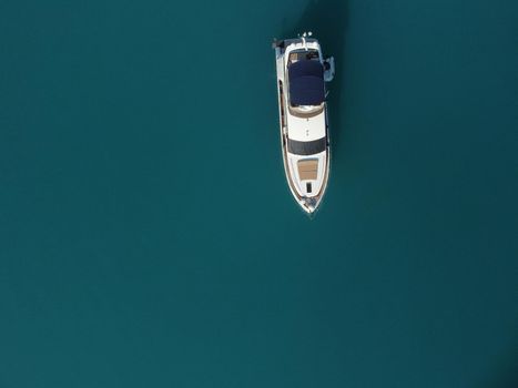 Aerial boat race. Luxury cruise trip. View from above of white boat on deep blue water. Aerial view of rich yacht sailing sea. Motor boat racing wave. Summer journey on luxury ship