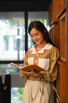 Peaceful woman reading interesting book in college library. People, knowledge and education concept.