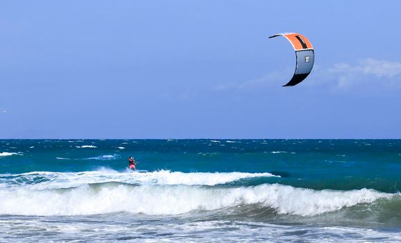 Alicante, Spainl- September 18, 2022: Surfer at Arenales del Sol beach under blue sky and wavy mediterranean sea