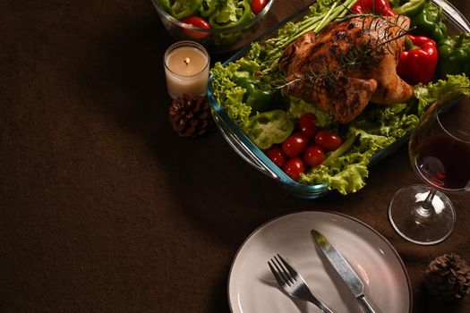 Above view of winter holiday table served, decorated with candles, roast turkey red wine on brown background.