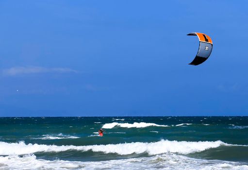 Alicante, Spainl- September 18, 2022: Surfer at Arenales del Sol beach under blue sky and wavy mediterranean sea