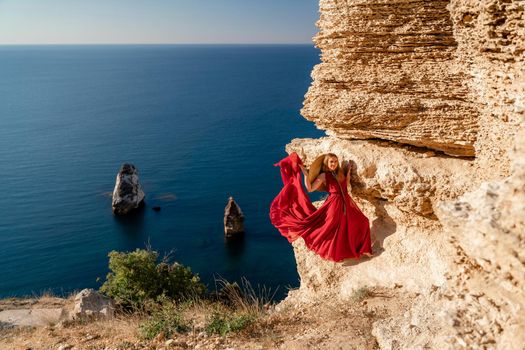 A woman in a red flying dress fluttering in the wind, against the backdrop of the sea