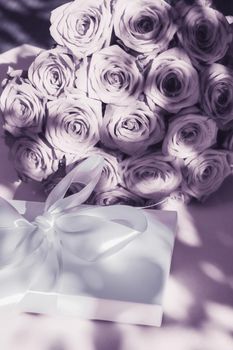 Happy holidays, luxe shopping and love gifts concept - Luxury holiday silk gift box and bouquet of roses on purple background, romantic surprise and flowers as birthday or Valentines Day present