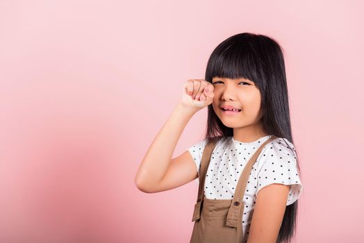 Unhappy children. Asian little kid 10 years old bad mood her cry wipe tears with fingers at studio shot isolated on pink background, child girl stress feeling sad unhappy crying