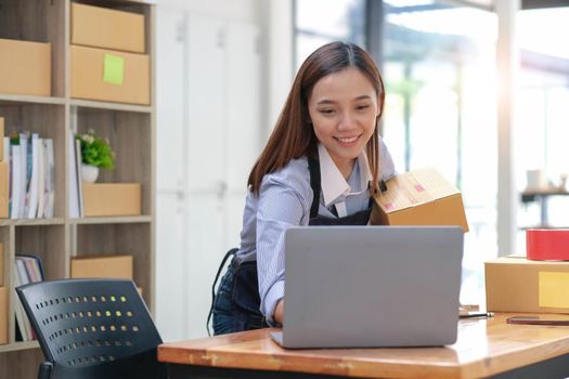 SME entrepreneur Business Young Asian freelance girl works with a laptop and box at home, about eCommerce, business, seller, Asian, employee, entrepreneur, box, merchant, Online SME business ideas,.