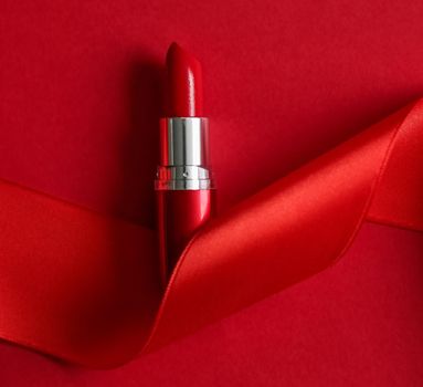 Cosmetic branding, glamour lip gloss and shopping sale concept - Luxury lipstick and silk ribbon on red holiday background, make-up and cosmetics flatlay for beauty brand product design