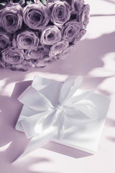 Happy holidays, luxe shopping and love gifts concept - Luxury holiday silk gift box and bouquet of roses on purple background, romantic surprise and flowers as birthday or Valentines Day present