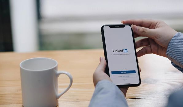 CHIANG MAI, THAILAND, JUL 27, 2022 : A women holds Apple iPhone Xs with LinkedIn application on the screen.LinkedIn is a photo-sharing app for smartphones..