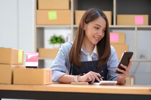 Startup small business entrepreneur SME, asian woman receive order on phone. Portrait young Asian small business owner home office, online sell marketing delivery, SME e-commerce telemarketing concept.