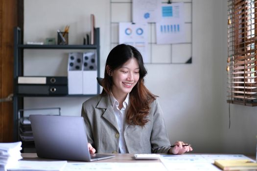 Portrait of smiling beautiful business asian woman working in office use computer with copy space