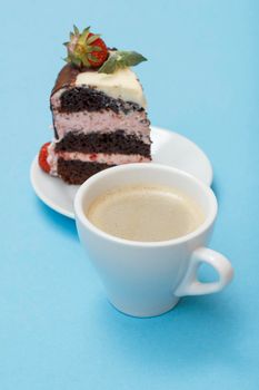 Cup of coffee and a piece of homemade chocolate cake decorated with fresh strawberries on a white plate on the blue background.