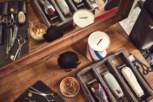 Hairdresser tools on wooden background. Top view on wooden table with scissors, comb, hairbrushes and hairclips, trimmer. Barbershop, manhood concept