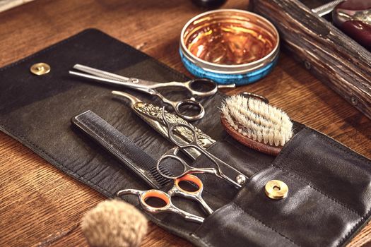 Hairdresser tools on wooden background. Top view on wooden table with scissors, comb, hairbrushes and hairclips, trimmer. Barbershop, manhood concept