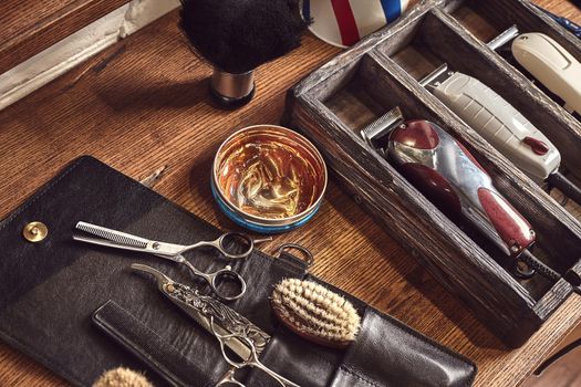 Hairdresser tools on wooden background. Top view on wooden table with scissors, comb, hairbrushes and hairclips, trimmer. Barbershop, manhood concept