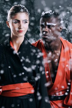 Cultural mystique. Fashion shot of a man and woman wearing oriental-style clothing in falling snow